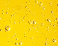 Texture of organic transparent gel or moisturizing lotion with many air bubbles smudged on bright illuminating yellow monochrome background. Concept of skin care cosmetic products. Trendy colors of the year 2021. Close-up and flat lay style