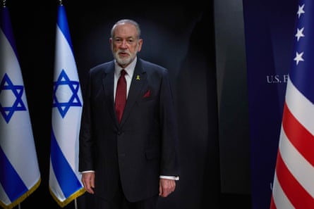 Mike Huckabee walks between Israeli and US flags before an interview in Jerusalem