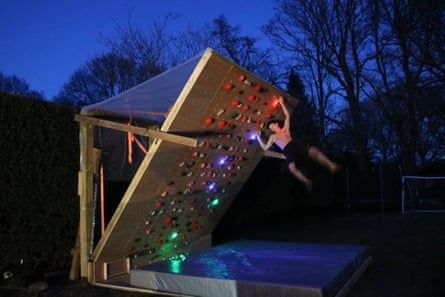 Toby climbs to the top of his climbing wall in his garden at night