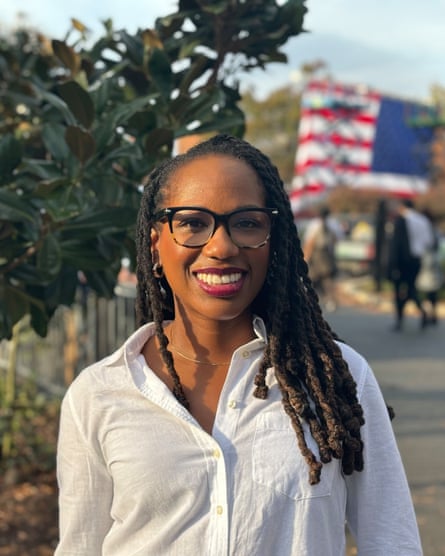A woman smiles in front of a US flag in the distance