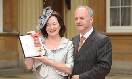 Dame Joan Ruddock holds up her DBE medal outside Buckingham Palace with Frank Doran beside her