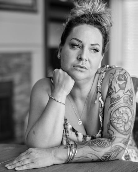 A woman, with arm tattoos, rests her hand on her chin