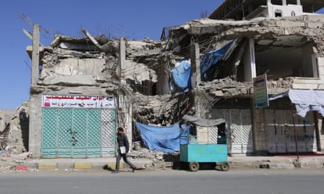 A Yemeni student walks past a building destroyed by an airstrike in Sana’a.