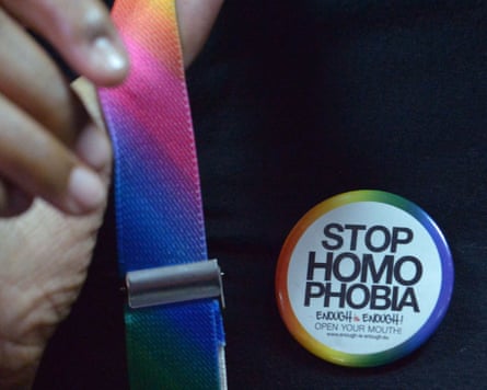 A person whose face is not seen wears a Stop Homophobia badge and rainbow braces.