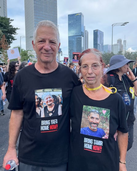 Erez and Adriana Adar in black T-shirts bearing images of family members taken hostage.