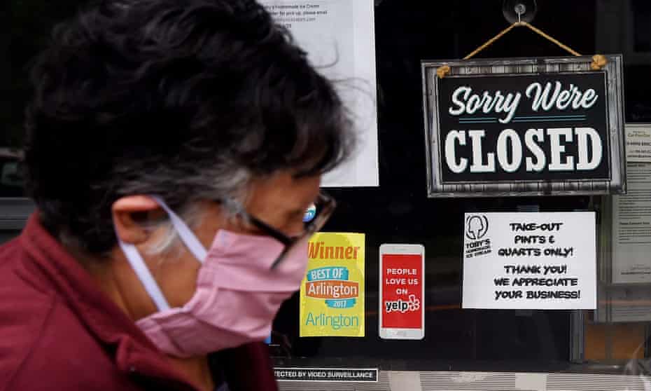 A woman wearing a face mask walks past a sign in the window of a closed food store
