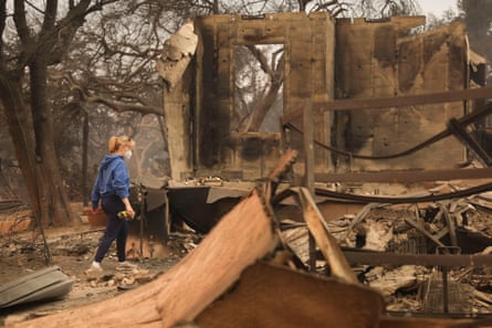 A woman looks through the remains of her home that was destroyed by a wildfire