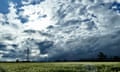 Clouds over a field with an electricity pylon in the distance