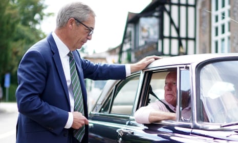 Nigel Farage talks to a local resident sitting in a car while out near his home in Westerham, Kent