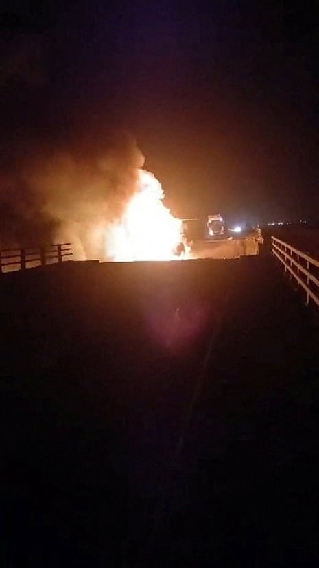 A fire burns on the damaged bridge.