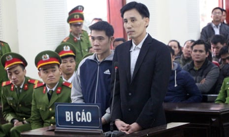 Vietnamese activist Hoang Duc Binh (centre L) standing inside the courtroom with co-accused Nguyen Nam Phong in Nghe An