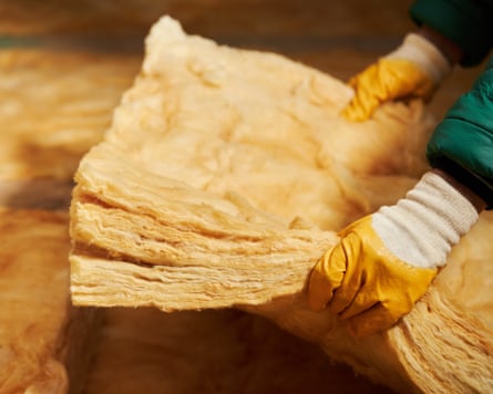 Construction worker thermally insulating house attic with glass wool. Attic renovation and insulation concept