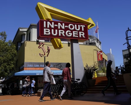 Pedestrians walk below an In-N-Out Burger restaurant sign in San Francisco.