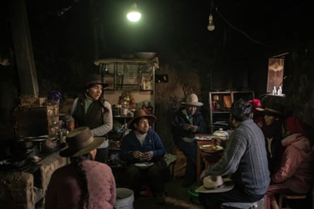 A Peruvian family eat together in a simple rural kitchen with stone walls