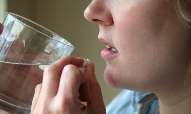woman taking pills with a glass of water