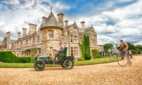Exhibits from the National Motor Museum Beaulieu. A 1920s motor car is pursued by a man on a penny farthing in front of the Montagu family mansion.