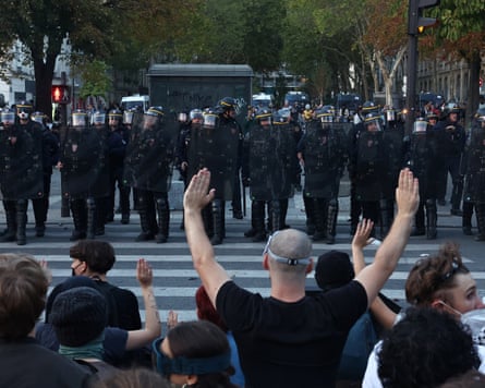 Protesters raise their arms as they face off with riot police