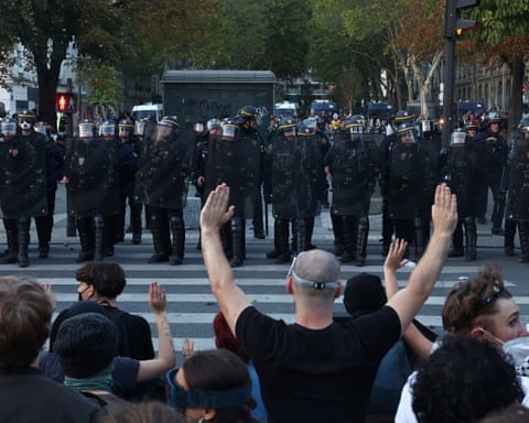Protesters raise their arms as they face off with riot police