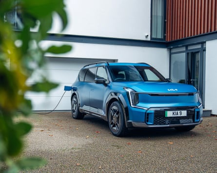 A blue Kia EV9 car parked on a home driveway