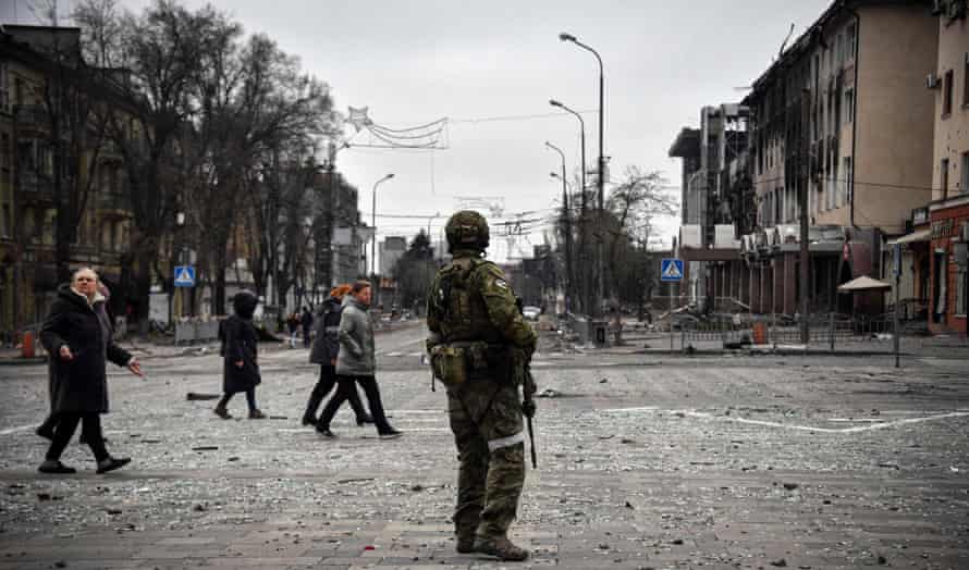 eople pass by a Russian soldier in central Mariupol on 12 April.
