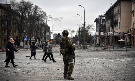 People pass by a Russian soldier in central Mariupol