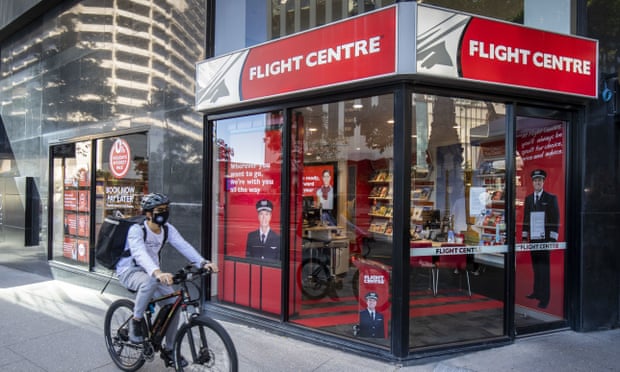 A cyclist rides past a Flight Centre store wearing a Covid-19 mask