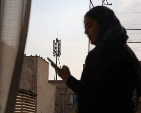 A woman using a smartphone with a communications tower in the background
