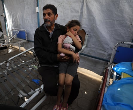 Ward Khalil sits on the knee of her uncle holding a doll