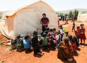 Idlib, Syria. Teacher Muheeb al-Essa uses a tent to write on while he takes a class at a camp for internally displaced people