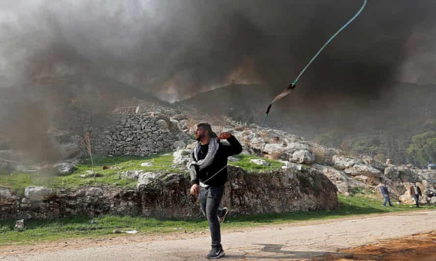 A Palestinian demonstrator hurls stones at Israeli troops during a protest against Jewish settlements.