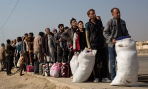 Men wait to go through and ID and security check at a civilian screening point after fleeing Mosul in Gogjali, Iraq.