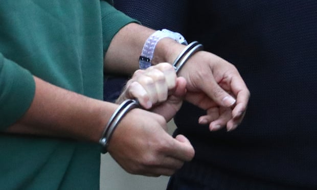A man being led into jail in handcuffs. 