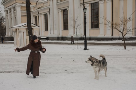 A woman plays with her dog in a snow covered field in Odesa.