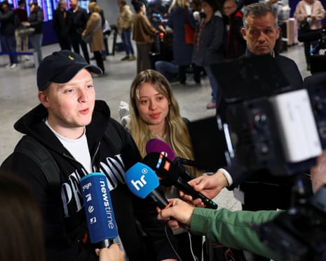 A young couple speaks to the media as they arrive from Muscat, Oman, amid the US-Israel conflict with Iran, at the airport in Frankfurt, Germany.