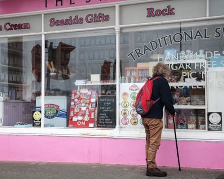 A person looking in a shop window displaying seaside gifts