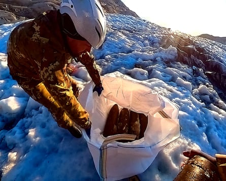 A soldier holds open a rubble sack containing a number munitions