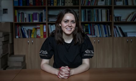 Kamila Ferenc sitting at a table with her hands folded, with a bookcase behind her
