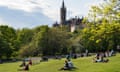 Students relaxing on lawns of Kelvingrove Park with Glasgow university in the distance in Scotland, United Kingdom