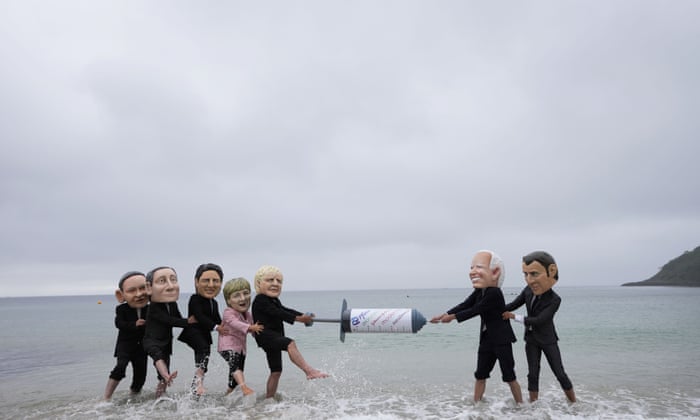 Activists wearing giant heads of the G7 leaders tussle over a giant Covid-19 vaccine syringe during an action of NGO’s on Swanpool Beach in Falmouth, Cornwall, England. Depicted from left to right, Japan’s Prime Minister Yoshihide Suga, Italy’s Prime Minister Mario Draghi, Canadian Prime Minister Justin Trudeau, German Chancellor Angela Merkel, British Prime Minister Boris Johnson, U.S. President Joe Biden and French President Emmanuel Macron.