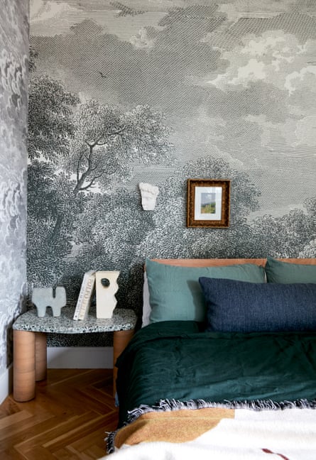 A bedroom with wallpaper printed with an engraving style landscape