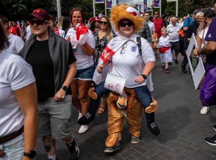 Fans, including one dressed as a lion, walk towards Wembley stadium.