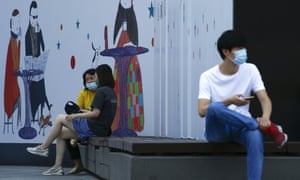 People wearing face masks as a precaution against coronavirus rest on the bench during a launch break outside an office building in Beijing, Thursday, 23 July 2020.