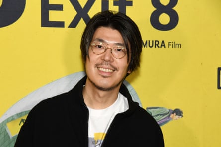 A Japanese man in round glasses and with floppy hair smiles at the camera.