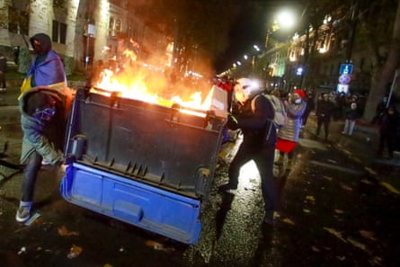 A group of protesters move a burning garbage container pouring into the streets following Georgian Prime Minister Irakli Kobakhidze’s announcement, rallying outside the parliament building in Tbilisi, Georgia, on Friday, Nov. 29, 2024. (AP Photo/Zurab Tsertsvadze)