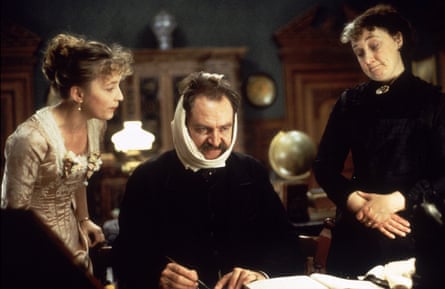 Lesley Manville and Kate Doherty stand either side of a seated Jim Broadbent who has a bandage wrapped under his chin and over his head. All dressed in period costume