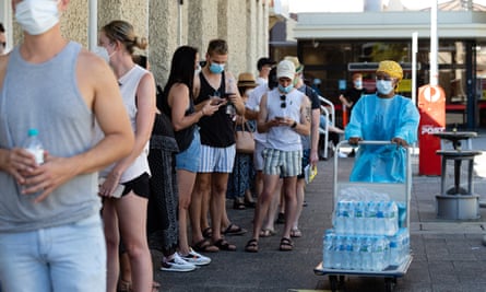 Medical staff hand out water to the long lines of people waiting to be tested for Covid-19 at Royal Perth Hospital on Sunday afternoon.