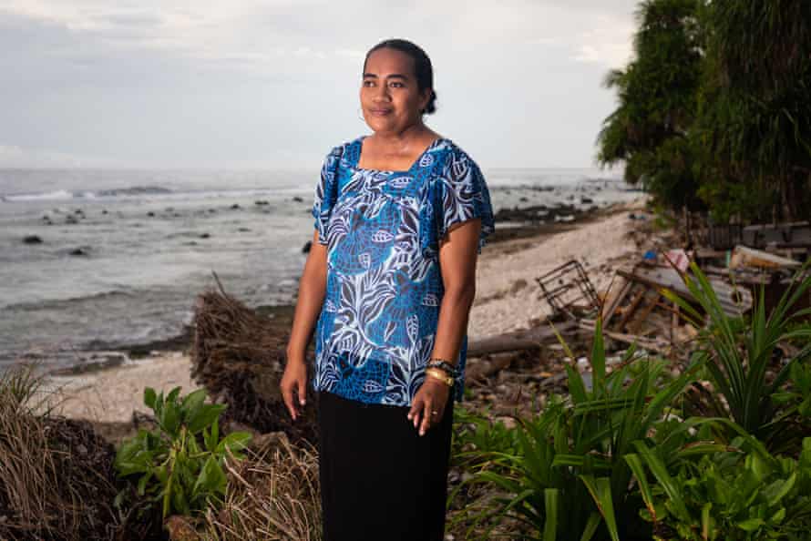 Enna Sione, 41, stands near the ocean which frequently floods her nearby home.