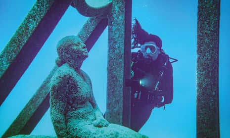 A scubadiver inspects a statue at Townsville’s Museum of Underwater Art.