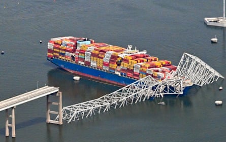 Ship with colorful cargo next to a white bridge pillar in the water