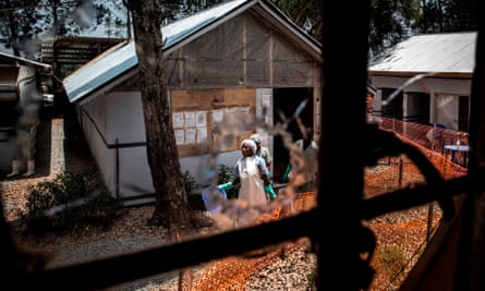 Health workers are seen through a bullet hole left in the window of an Ebola treatment centre in Butembo, which was attacked in March